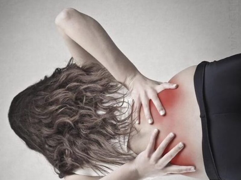 A person holding their lower back, indicating back and leg pain