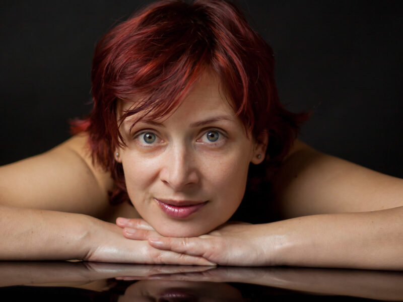 A woman looking closely at her face in a bathroom mirror